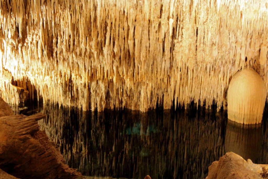 Lots of stalactites reflected in the clear water in the Cuevas Del Drach