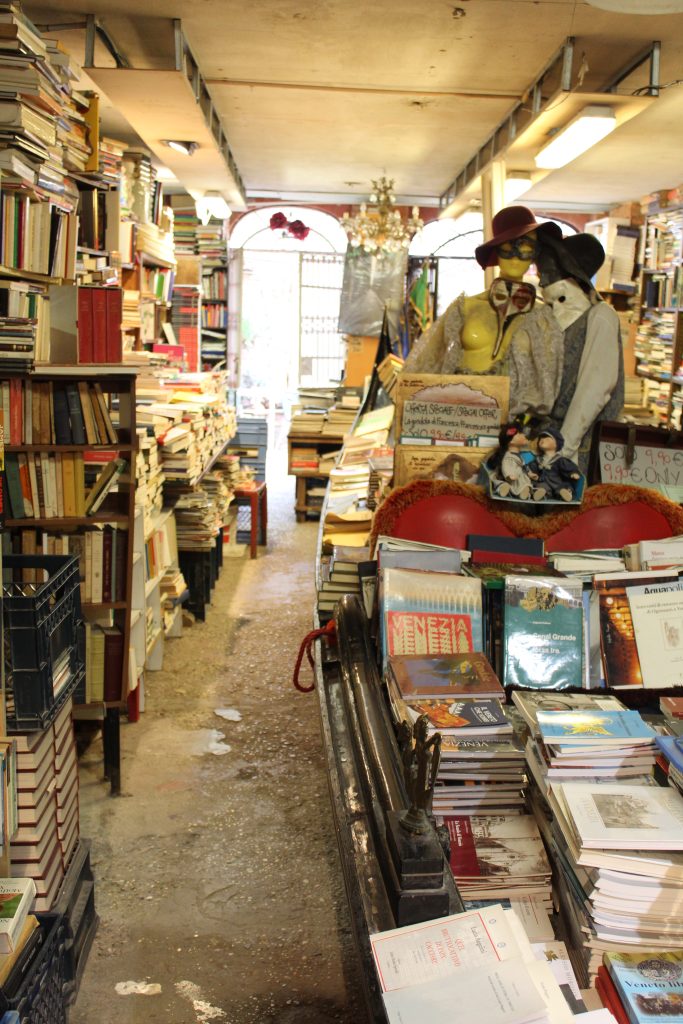 A gondola full of books inside Libreria Acqua Alta