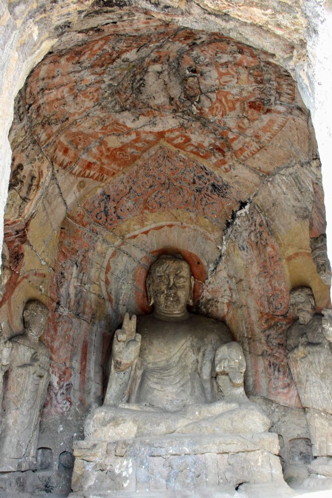 Statue of a buddha with a intricately painted ceiling