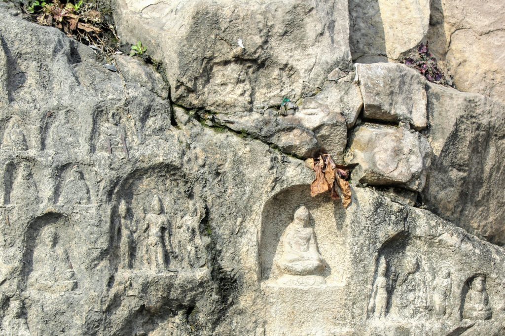 Some very small carvings at Longmen Grottoes with a small plant for scale.