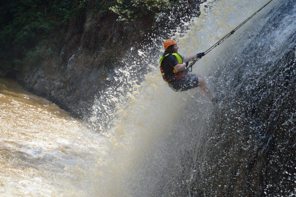 Photo of myself halfway down a waterfall holding onto abseiling rope.