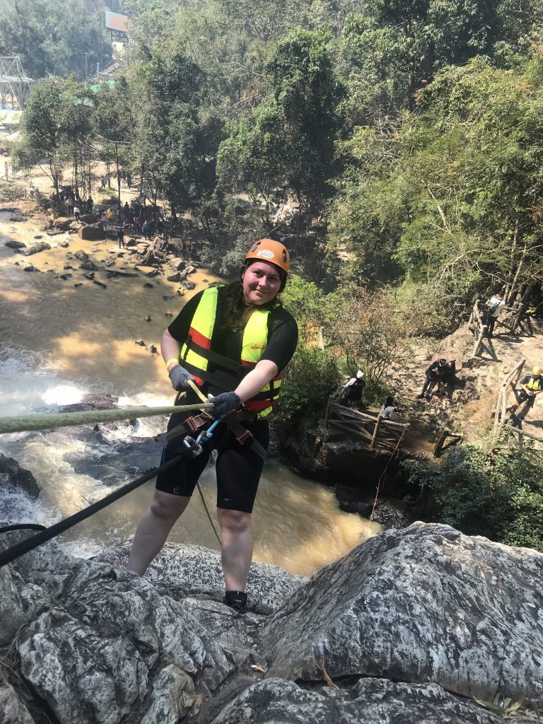 Photo of myself at the edge of a cliff holding a rope, ready to start abseiling waterfalls in Da Lat.