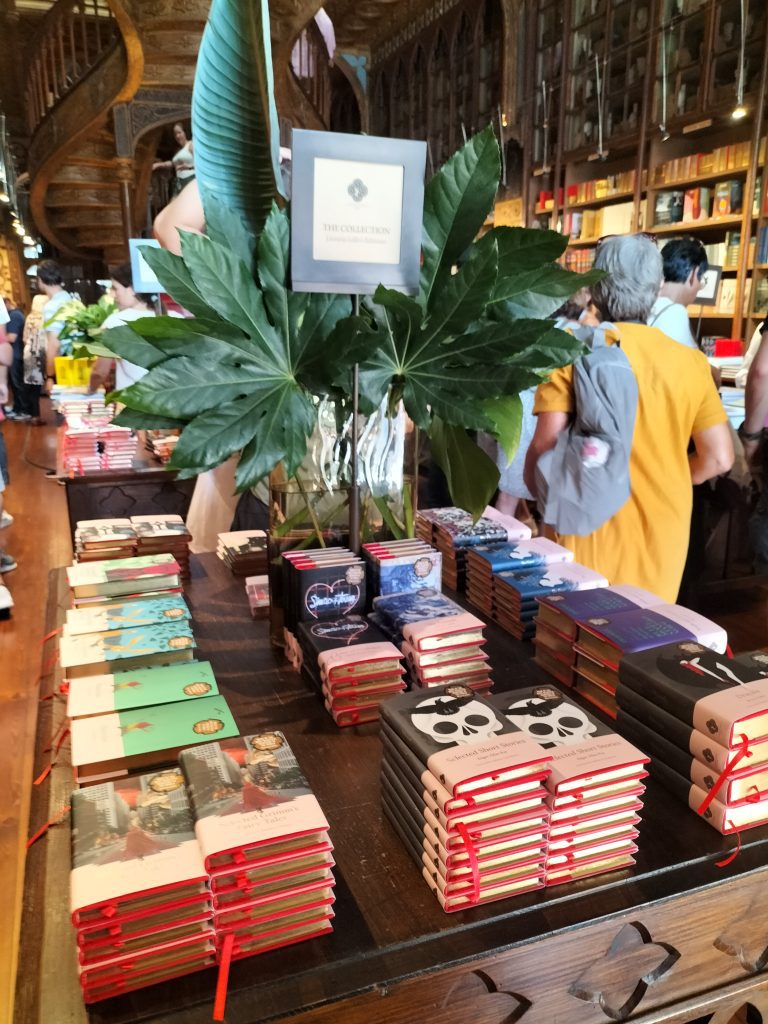 Photo of a table with stacks of books, with covers exclusive to Livraria Lello