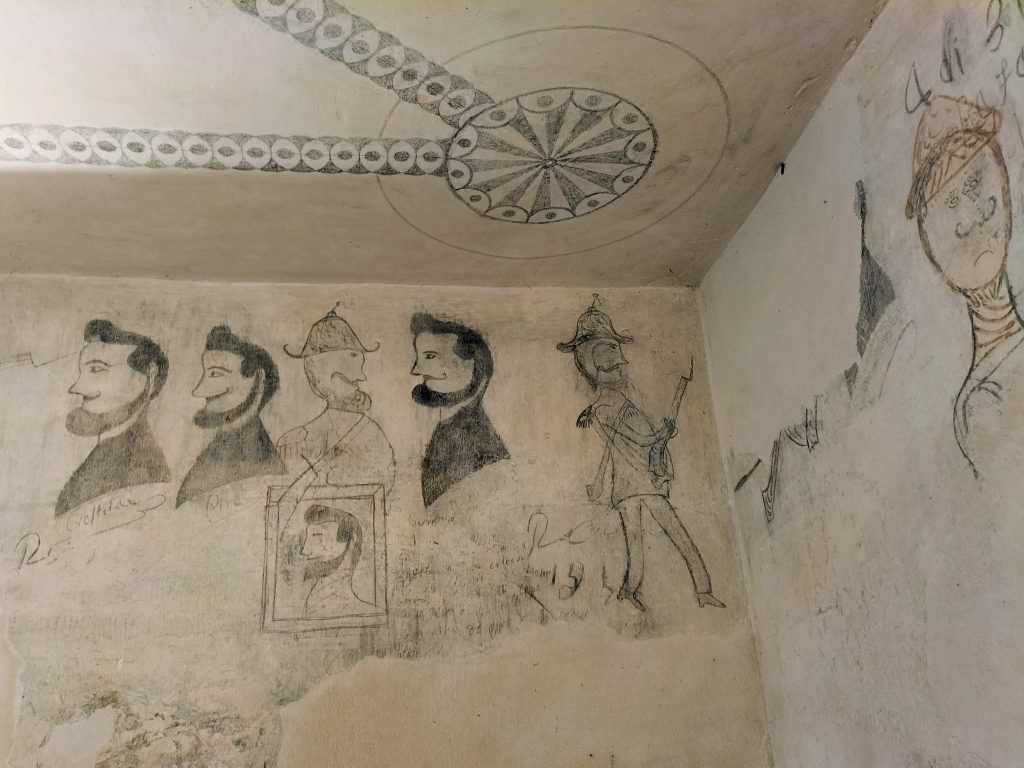 Photo showing graffiti of various men drawn by prisoners.