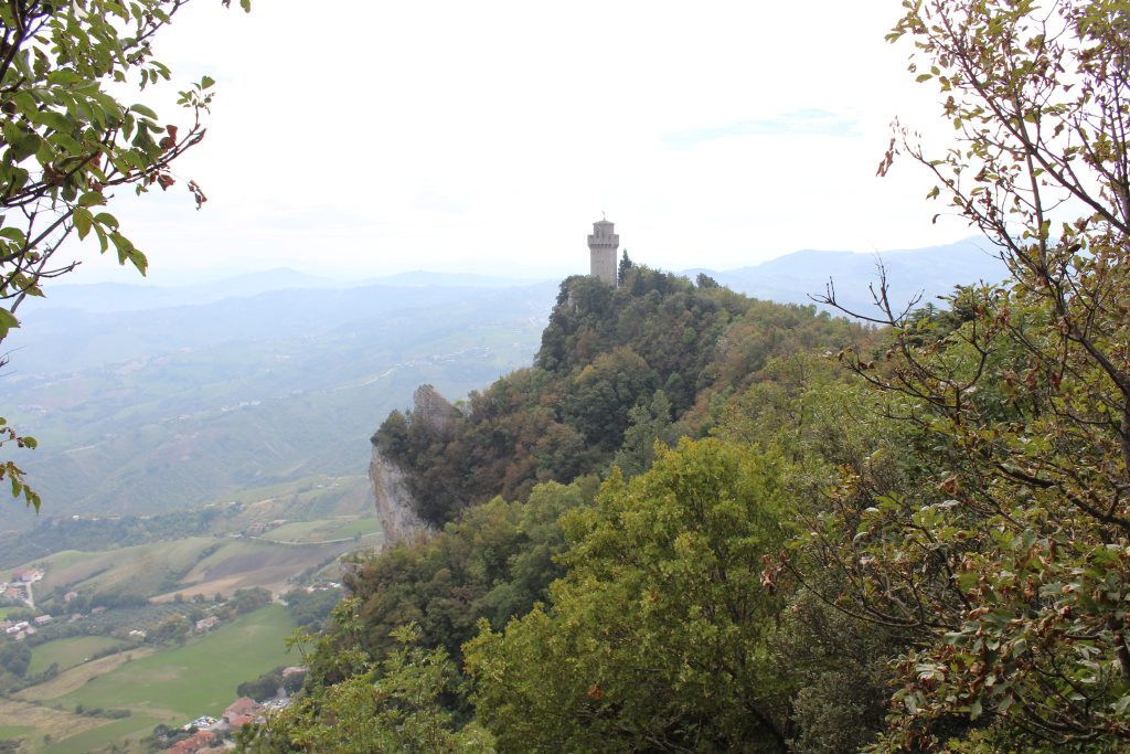 A view of the third tower of San Marino, framed by trees.