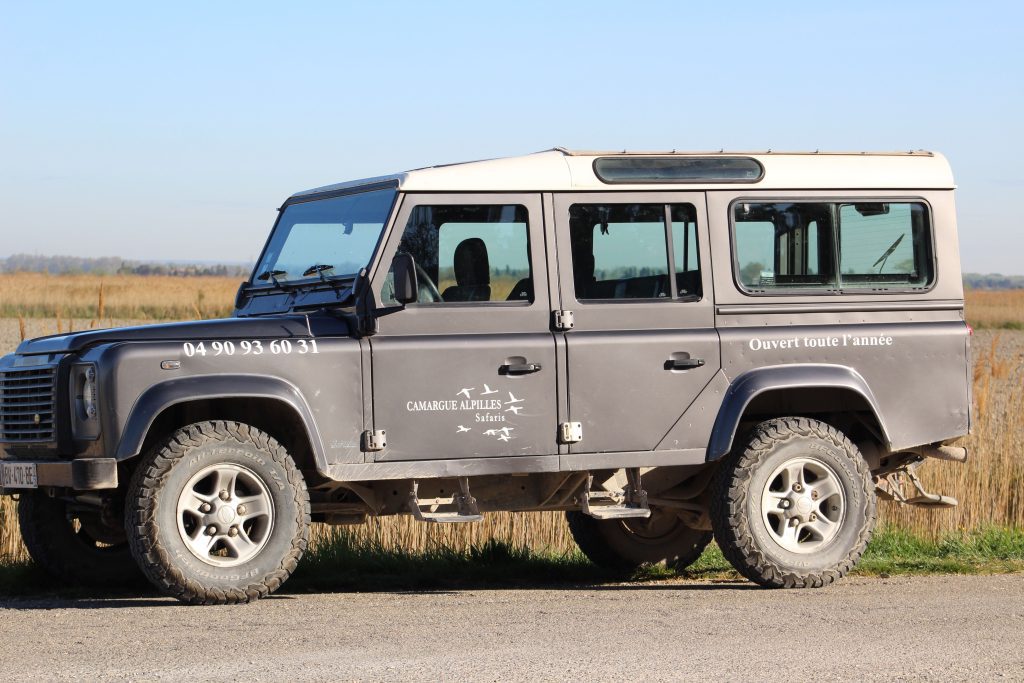 Photo of a grey jeep parked at the side of a road, with adventising for a day trip to the Camargue on the side. 