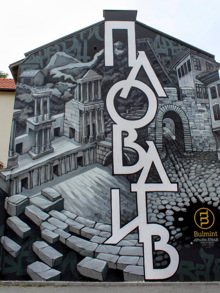 Photo of a mural saying Plovdiv in Cyrillic with pictures of the threatre and the old town.