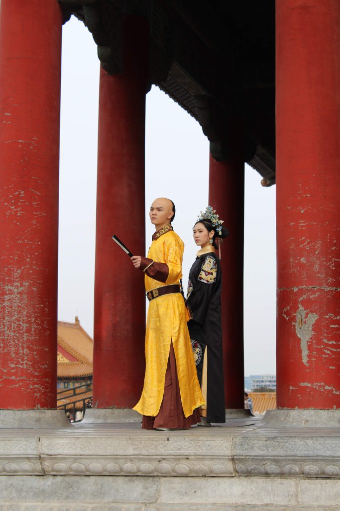 Photo of a couple dressed in traditional outfits standing beside some pillars in the Forbidden City.
