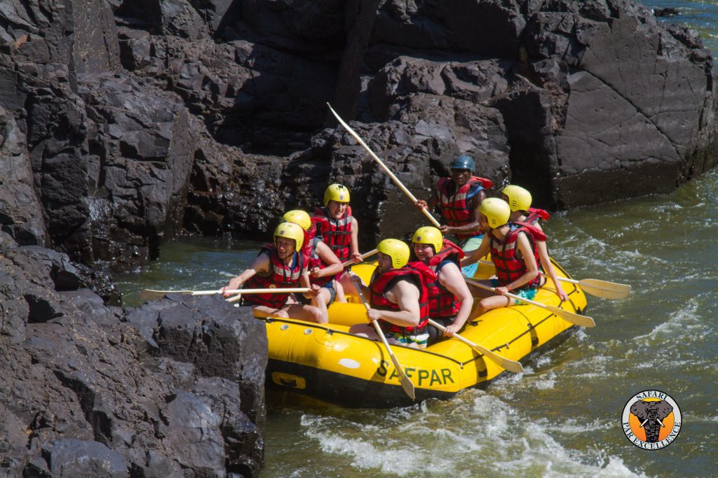 Photo of white water raft stuck beside some rocks.