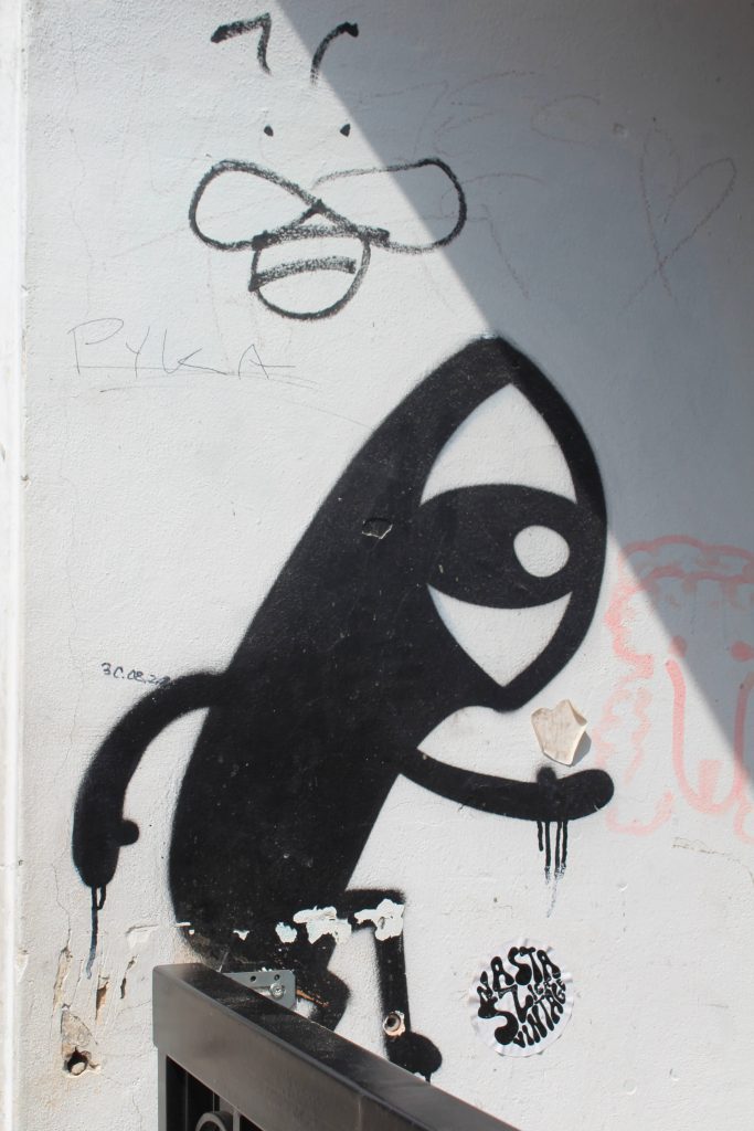 Photo of a black and white character with a huge eye for the face painted on a wall.