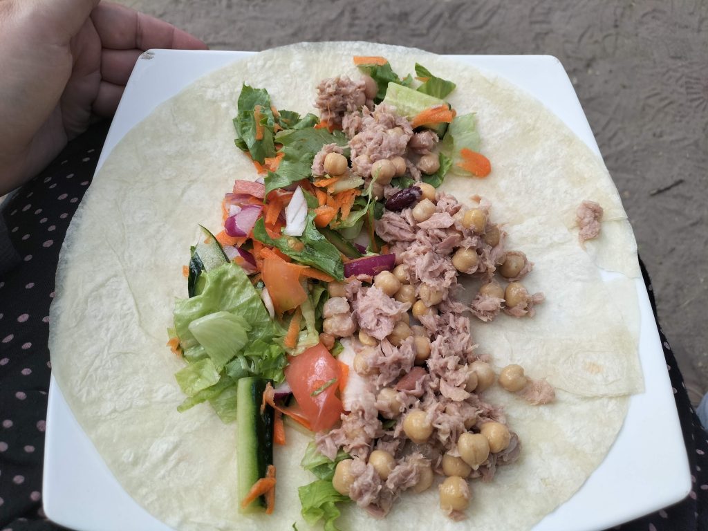 Photo of a white wrap. In the wrap is tuna, chickpeas and salad.