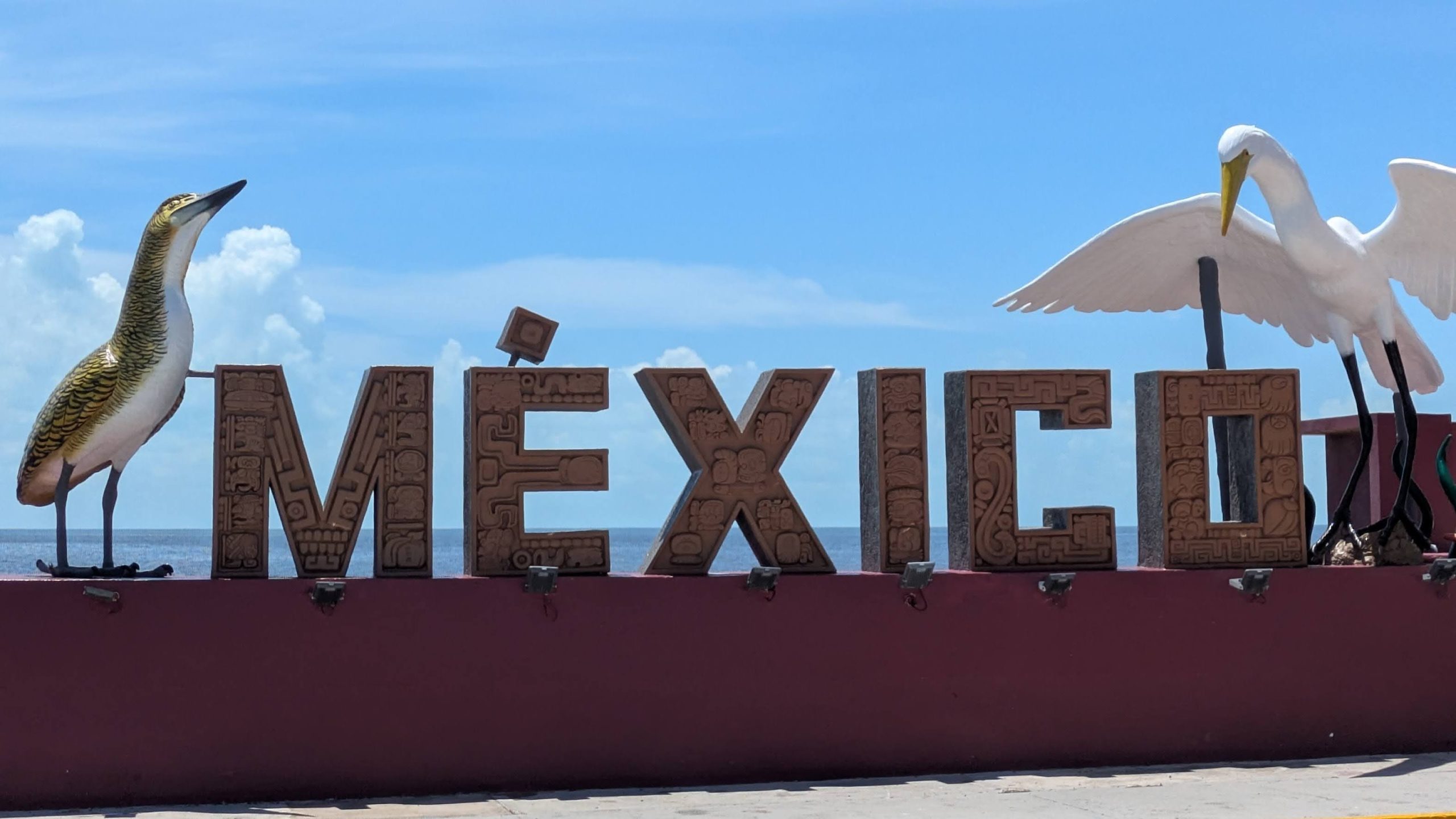 Photo of a sign saying Mexico. On either side of the sign are birds.